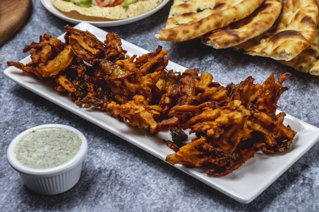 Indulge in the authentic preparation and fresh, high-quality ingredients used in crafting the Best and Popular Crispy Onion Bhaji at Tandoori Bliss